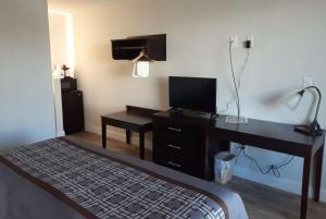 a hotel room with a desk with a television and a bed at Travelodge by Wyndham Virginia Beach Bay Beach in Virginia Beach +9 photos