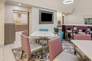 a waiting room with tables and chairs and a tv at La Quinta by Wyndham North Orem in Orem