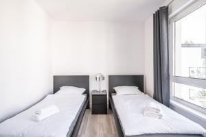 two beds in a room with two windows at RentPlanet - Apartamenty Na Grobli in Wrocław
