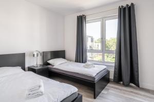 a bedroom with two beds and a window at RentPlanet - Apartamenty Na Grobli in Wrocław