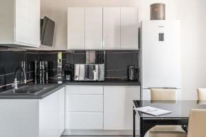 cocina con armarios blancos y nevera en RentPlanet - Apartamenty Na Grobli en Breslavia