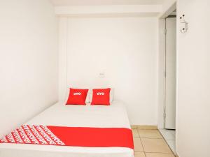 uma cama num quarto com duas almofadas vermelhas em OYO Hotel Vintage, São Paulo em São Paulo