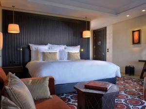 a hotel room with a large bed and a couch at Fairmont Royal Palm Marrakech in Marrakesh