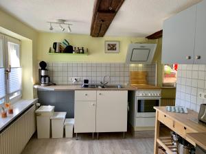 una cocina con armarios blancos y fregadero en Ferienwohnung Pusteblume en Wildemann