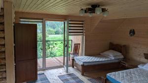 Zimmer mit einem Bett und einem Balkon mit einem Fenster in der Unterkunft Gostynna Rodyna in Izky