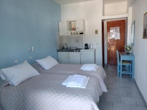 two beds in a small room with a kitchen at Kamelia in Kokkari
