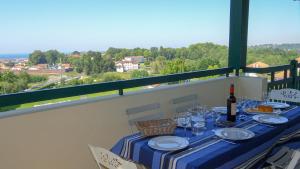 a table with a bottle of wine and glasses on a balcony at Ziburu Mendi - Appartement Calme, Vue Mer, Parking - WiFi in Ciboure