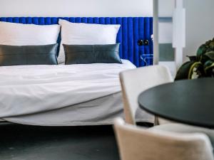 a bedroom with a bed with pillows and a table at Pastel Blue Silesian Place Apartments in Katowice