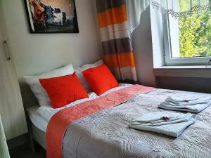 Un dormitorio con una cama con almohadas rojas y una ventana en Zachodnia - 3 Pokoje, Manufaktura Parking, , FV en Lodz