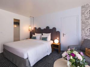 エクスレバンにあるMercure Aix-les-Bains Domaine de Marlioz Hôtel & Spaの大きなベッドとソファが備わるホテルルームです。