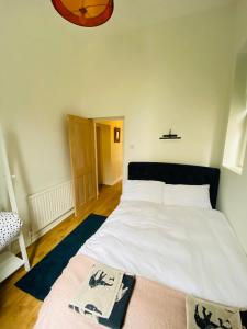 a bedroom with a large white bed with a black headboard at Lovingly Restored Victorian Apartment in Hastings in Hastings