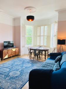 a living room with a table and a blue rug at Lovingly Restored Victorian Apartment in Hastings in Hastings