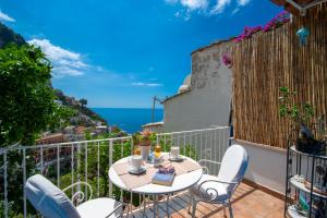 a table and chairs on a balcony with a view of the ocean at Casa Bellina in Positano
