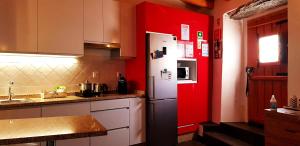 a kitchen with a white refrigerator and a red wall at Charme de Monsaraz in Monsaraz