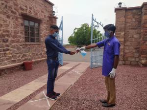 Dois homens estão a apertar as mãos em frente a um edifício. em Bijolai Palace - A Inde Hotel , Jodhpur em Jodhpur