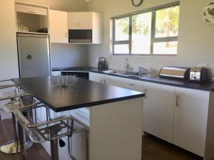 a kitchen with white cabinets and a black counter top at C’est La Vie in Balgowan