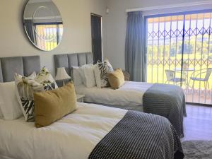 a bedroom with two beds and a mirror and a window at C’est La Vie in Balgowan