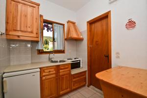 a kitchen with wooden cabinets and a sink and a window at Korinas House in Agnontas +6 photos