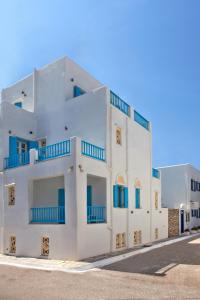 - un bâtiment blanc avec des balcons bleus dans une rue dans l'établissement TINOS AQUA PALAZZO, à Tinos
