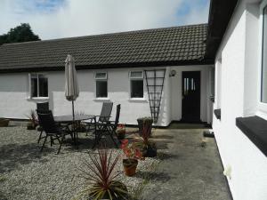 a white house with a table and chairs and an umbrella at West Point B&B in Bude