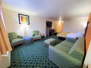 a hotel room with a bed and a couch and chairs at Baymont by Wyndham Santa Fe in Santa Fe