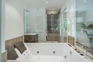 a white bath tub in a bathroom with a sink at Wellholidays 19 - Balnéo, terrasse et piscine partagée in Boersch