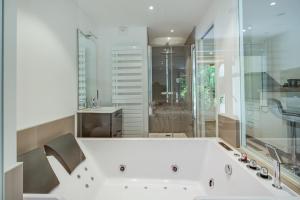 y baño con bañera blanca y lavamanos. en Wellholidays 19 - studio balnéo et terrasse piscine, en Boersch