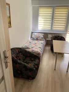 een kleine kamer met een bed en een tafel bij Stara Piekarnia - Apartament Dworcowa in Olsztyn