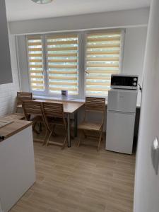 a kitchen with a table and chairs and windows at Stara Piekarnia - Apartament Dworcowa in Olsztyn