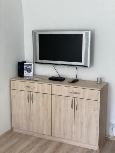 a flat screen tv sitting on top of a wooden cabinet at Stara Piekarnia - Apartament Dworcowa in Olsztyn