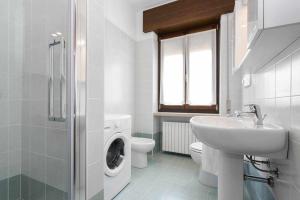La salle de bains blanche est pourvue d'un lavabo et d'un lave-linge. dans l'établissement Ortaglia, à Torri del Benaco