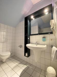 ein Badezimmer mit einem Waschbecken, einem WC und einem Spiegel in der Unterkunft REGIOHOTEL Wittekind Burg in Burg bei Magdeburg