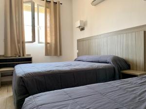 a bedroom with two beds and a window at Hotel Les Palmiers En Camargue in Saintes-Maries-de-la-Mer
