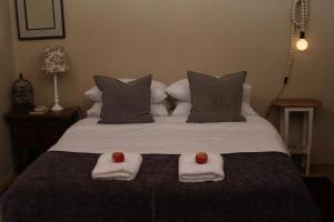 a bed with two towels and two apples on it at The Apple Blossom Cottage in Villiersdorp