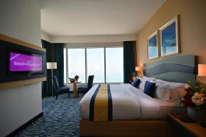 a hotel room with a bed and a flat screen tv at Harbour Suites Hotel in Manama
