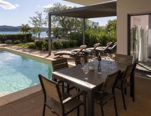 a wooden table and chairs on a patio with a pool at Villa Lu-Ma Beachfront with Heated Pool in Turanj