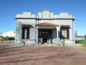 una casa blanca con dos ventanas en un camino de tierra en Casa Mansa Puro Campo en Lobos