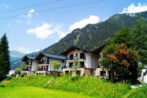 a building on a hill with mountains in the background at Alpenchalet Montafon in Gaschurn