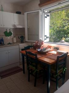 a kitchen with a wooden table with chairs and a window at Yria Suite Zakynthos in Katastárion