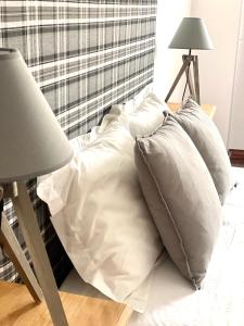 uma pilha de almofadas numa cama ao lado de um candeeiro em Brick Ocean Apartment na Nazaré