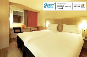 ein großes weißes Bett in einem Hotelzimmer in der Unterkunft ibis Porto Centro São Bento in Porto