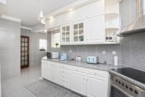 Una cocina blanca con gabinetes y electrodomésticos blancos. en Sunrise Terrace Peniche, en Peniche
