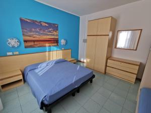 1 dormitorio con 1 cama con pared azul en Appartamenti Vanin, en Cavallino-Treporti