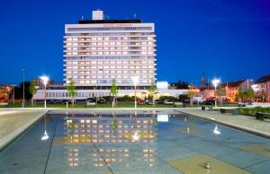 um grande edifício com uma piscina reflectora em frente em Hotel Cernigov em Hradec Králové