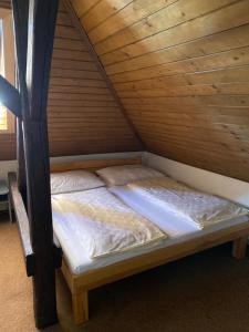 a bed in a room with a wooden ceiling at Hotel Praděd Rýmařov in Rýmařov