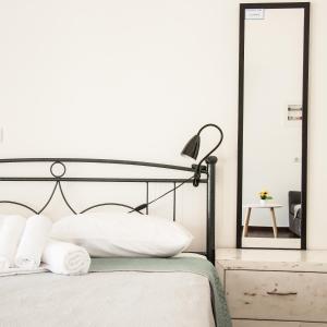 a bedroom with a bed with white sheets and a mirror at Ag.apostoloi studios in Agioi Apostoli