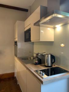 a kitchen with white cabinets and a stove top oven at Ty Carreg Fach Staycation Cottage Cardiff in Cardiff