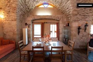 a dining room with a wooden table and a stone wall at 19th Century Magical House in Galilee in ‘Eilabūn