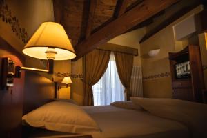 a bedroom with a bed with a lamp and a window at Hotel Le Bouquet - Adults Only in Cogne