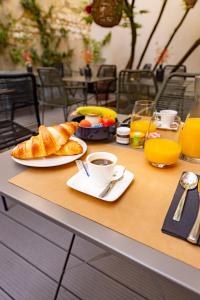 uma mesa com um pequeno-almoço de croissants, café e sumo de laranja em Hôtel Azur em Reims